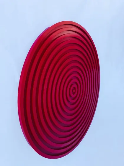 An angled shot of the red circular art, capturing the way light reflects off its glossy, protective finish.