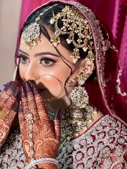 A beautiful, shy pose that highlights the detailed henna and the stunning bridal jewellery.