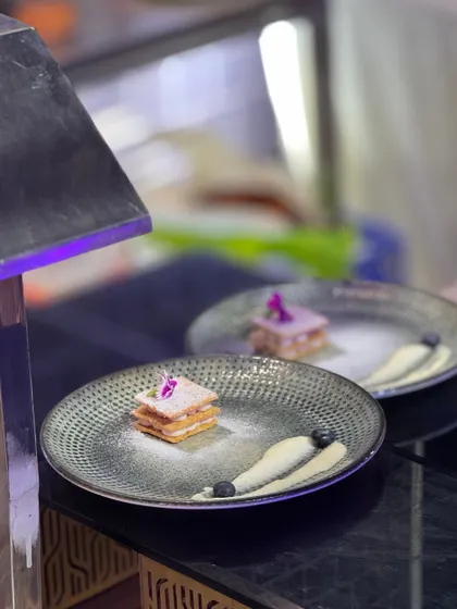 A deconstructed dessert masterpiece. This layered pastry is presented with artistic swipes of cream and carefully placed berries, turning a sweet treat into a piece of edible art.
