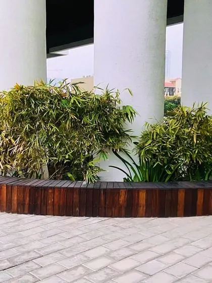 This curved wooden planter bench wraps around the large pillars of the building, softening the architecture and creating a natural, organic feel in a concrete environment.
