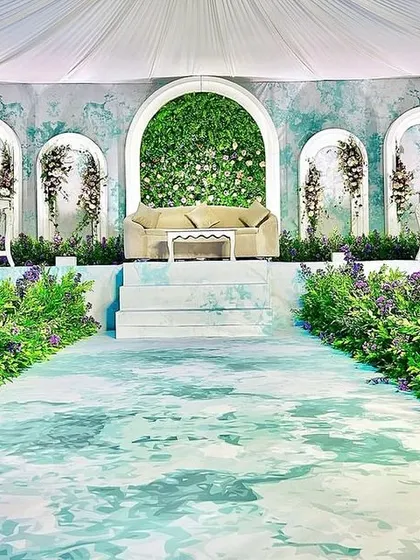 An ethereal and dreamy stage design. We used a watercolor-effect backdrop, a green floral arch, and a pathway lined with lavender for a truly unique and artistic wedding setup.