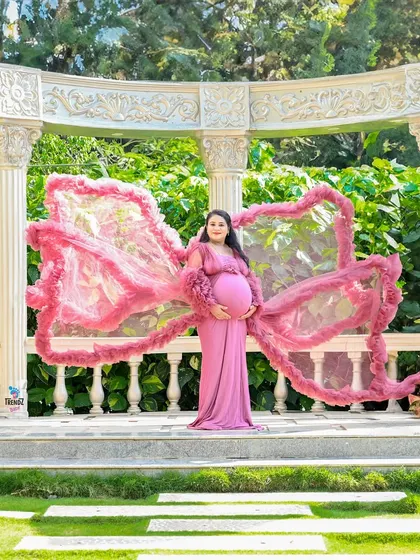Another creative use of a flowing gown outdoors. The gown is shaped like butterfly wings against the backdrop of a beautiful garden structure.