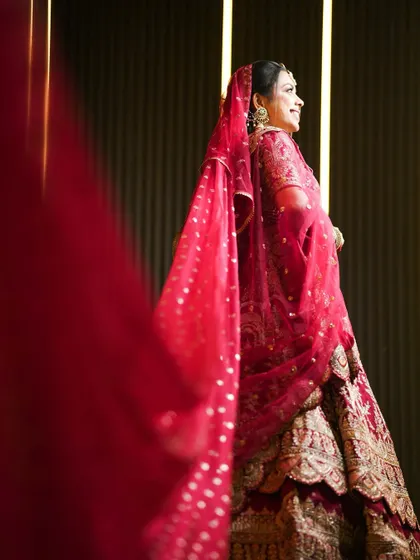 A smiling bridal portrait, with the red veil adding a soft frame to her face.