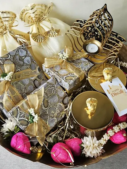 This is the essence of my craft, a grand festive hamper brimming with joy. Inside this beautiful basket, you will find agate-printed gift boxes, gourmet treats in delicate potlis, and an elegant hamsa-shaped candle holder, all curated to make your celebration truly unforgettable.