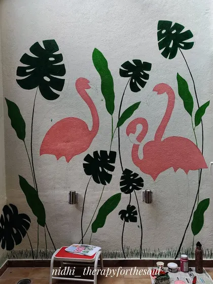 The flamingo mural in its early stages. The background leaves and the basic shapes of the flamingos are painted first to establish the overall composition.