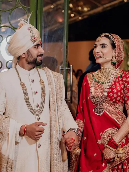 The happy couple at their Delhi wedding. The bride's classic red lehenga stands out beautifully against the sophisticated, neutral tones of our mandap design.