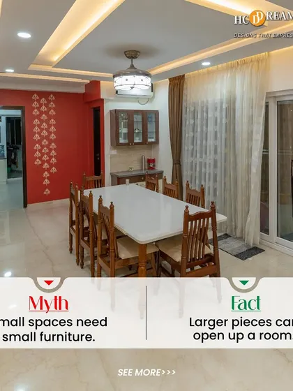 Debunking the myth that small spaces need small furniture. Here, a large dining table anchors the room, making the space feel more generous and usable, complemented by a bold red accent wall for character.