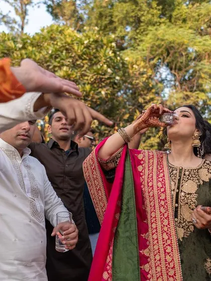 A true Delhi Punjabi wedding must-have: the bride taking a shot with her friends and family cheering her on.