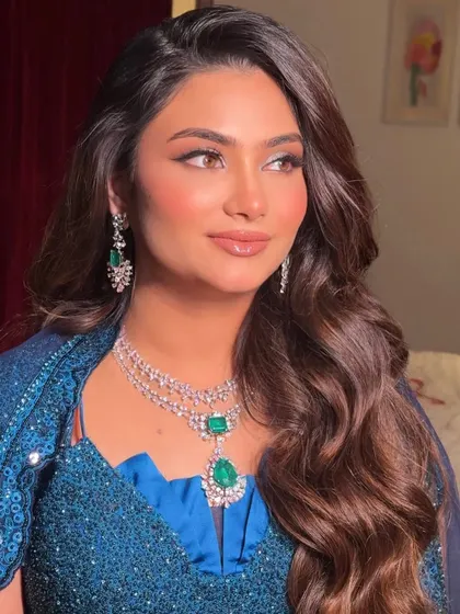A close-up portrait showcasing her radiant skin and perfectly defined cat-eye liner. The makeup enhances her beautiful features and complements her stunning jewelry.