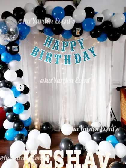 A simple and clean balloon arch in blue, black, and white. The 'Happy Birthday' banner and marquee letters make it a complete and personal setup.