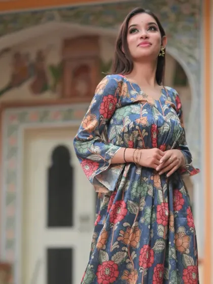 A floral print dress with bell sleeves, set against a historic backdrop. The muted colors and flowing silhouette give it a romantic, timeless feel.