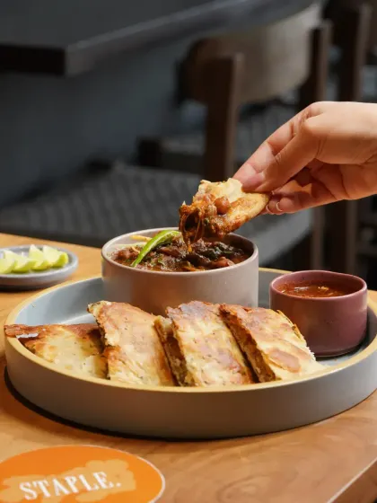 A hearty and traditional plate of chole with kulcha. The styling emphasizes the rich textures of the gravy and the fluffiness of the bread, creating a comforting and appetizing image.