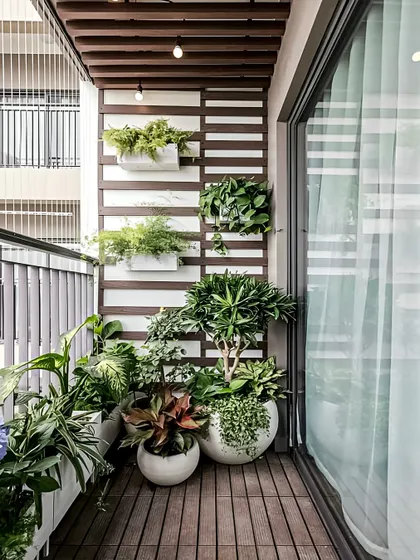 This balcony showcases a clean, contemporary look with a mix of large and small planters. The white and brown color scheme for the planters and wall panels creates a cohesive design that makes the greenery pop.