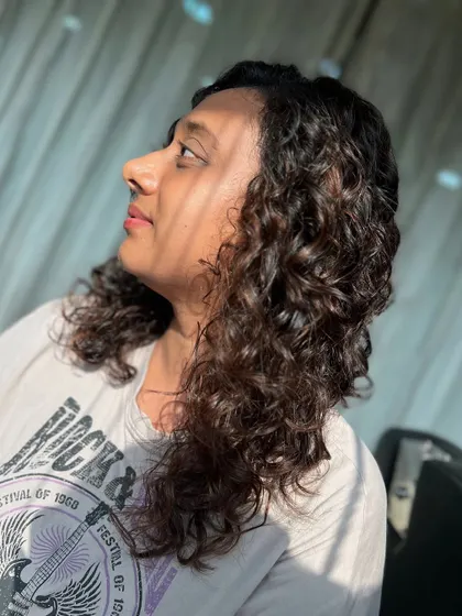 A side profile of these sun-kissed brown curls. The light brings out the subtle highlights and shows off the healthy shine.