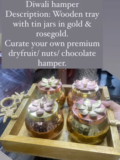 This premium Diwali hamper features a wooden tray with ornate handles, holding beautiful gold and rose gold tin jars. You can curate your own by filling them with dry fruits, nuts, or chocolates.