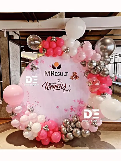 A custom circular backdrop designed for a corporate Women's Day celebration, featuring a cherry blossom theme and a pink and silver balloon garland.