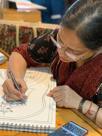 A student carefully inks a detailed folk art drawing, a crucial step that requires a steady hand.