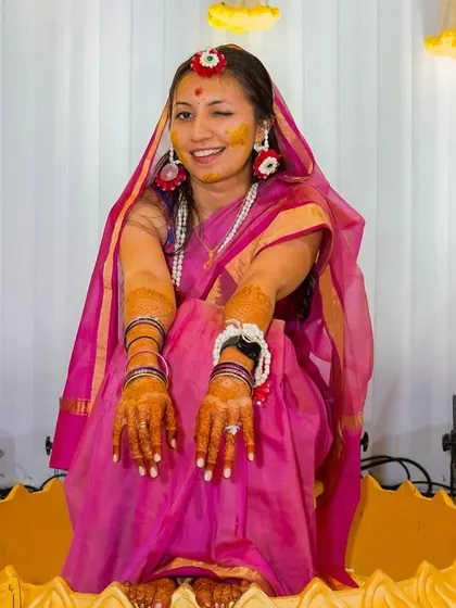 A playful wink from the bride, covered in turmeric and floral jewellery, capturing the fun spirit of the haldi ceremony.