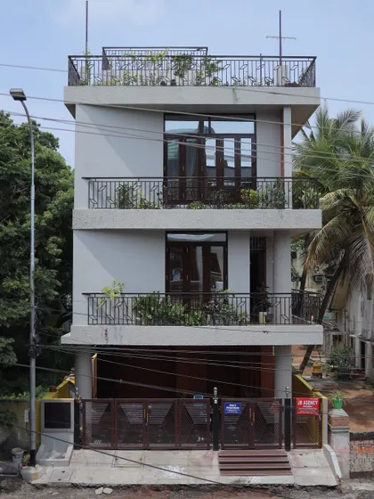 The facade of the Ram's Anugraham residence, designed for a compact urban plot. The design maximizes space with balconies on each level, creating green pockets and functional outdoor areas.
