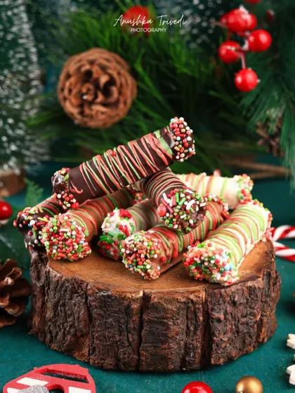 Christmas-themed chocolate cigar rolls, drizzled with red, green, and white chocolate and covered in sprinkles.