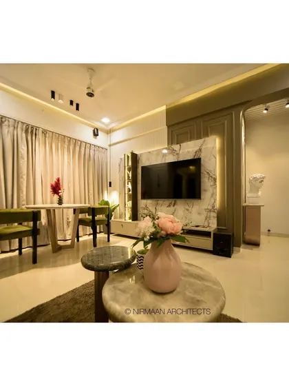 The dining area in this modern classic living room is positioned to take advantage of natural light. The marble-clad TV unit and elegant furniture create a cohesive and sophisticated look.