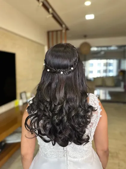 A romantic half-updo for a white wedding. I created a delicate braid crown and added small pearls for a touch of elegance, letting the rest of the hair flow in soft curls.