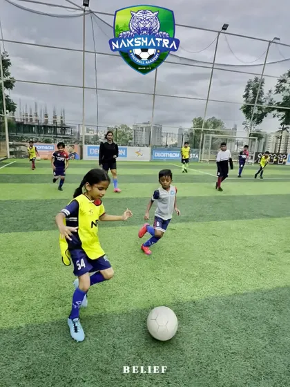 Every goal begins with a single kick of belief. A young girl dribbles the ball with determination during a co-ed training session.