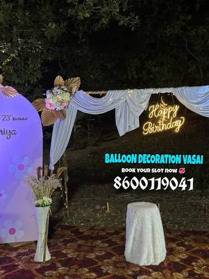 A rustic and chic 23rd birthday setup for an outdoor party. The decor includes a custom backdrop, a draped arch, and floral arrangements.