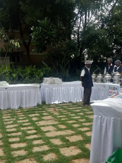 An outdoor buffet setup under the trees. Our team of servers is ready at their stations, ensuring a seamless dining experience for guests at this garden event.