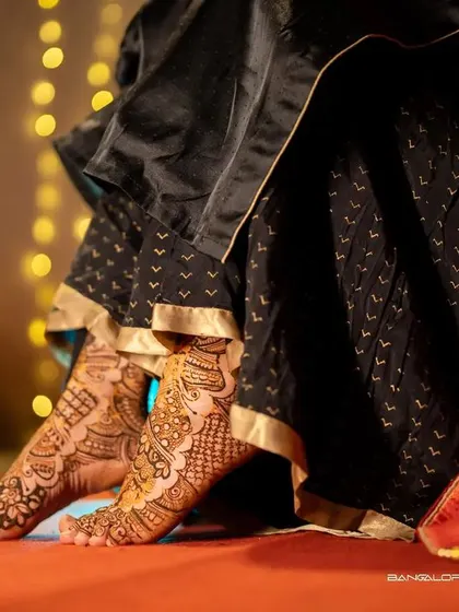 A detailed shot focusing on the bride's feet, adorned with intricate Mehendi. The patterns tell a story of tradition and beauty.