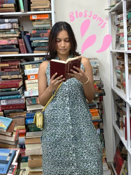 Getting lost in a book at Blossoms, with some pink petal doodles floating around me.