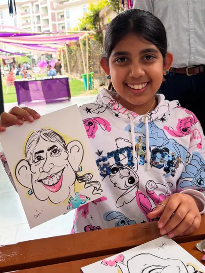 A young guest at an ISB Alumni Meetup, happy with her fun caricature.