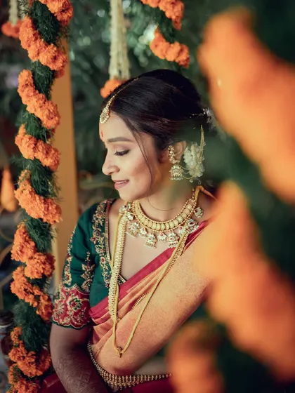 A serene bridal portrait, capturing a moment of quiet contemplation amidst the wedding celebrations. The focus is on her intricate jewelry and the beautiful texture of her saree.