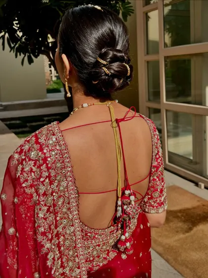 A look at the classic bridal bun. This hairstyle is not only elegant but also practical, keeping the focus on her beautiful backless blouse and jewelry.