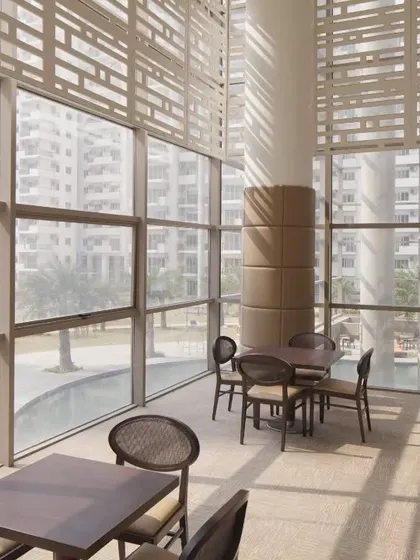 The MGF Palm Drive clubhouse in Gurugram features double-height glass walls and sun-shading screens. This design maximizes natural light and views, creating a strong connection to the surrounding landscape.