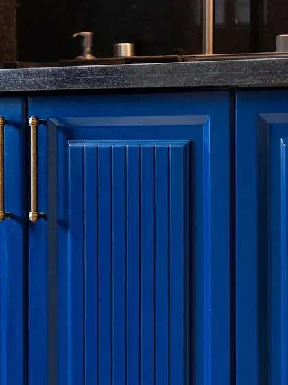 A close-up of royal blue kitchen cabinets with a vertical groove pattern and elegant brass handles. This showcases the level of detail in my custom cabinetry.