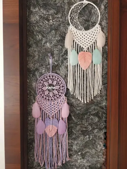Two personalized macrame dreamcatchers hanging side-by-side. One features the name 'Keira' in a pastel design, while the other is a half-moon macrame piece, showing our range of styles.
