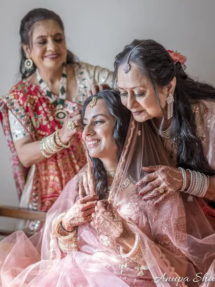 A bride is lovingly attended to by her mother and mother-in-law, a beautiful portrait of the two most important women in her life.