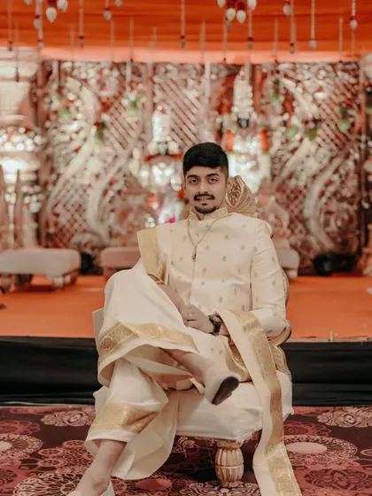 A confident groom posing on his wedding stage in traditional attire.