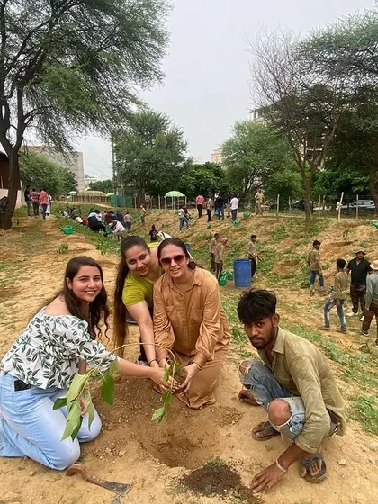 Volunteers from Estee Advisors smile for the camera while planting a sapling with our on-ground team member.