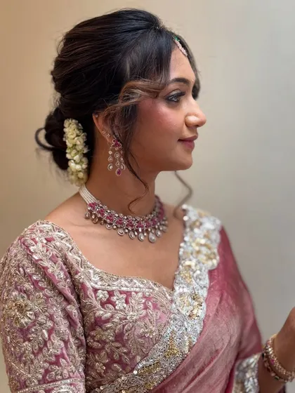 A side profile showing her elegant floral bun hairstyle. The soft tendrils framing her face add a touch of romance to the look.