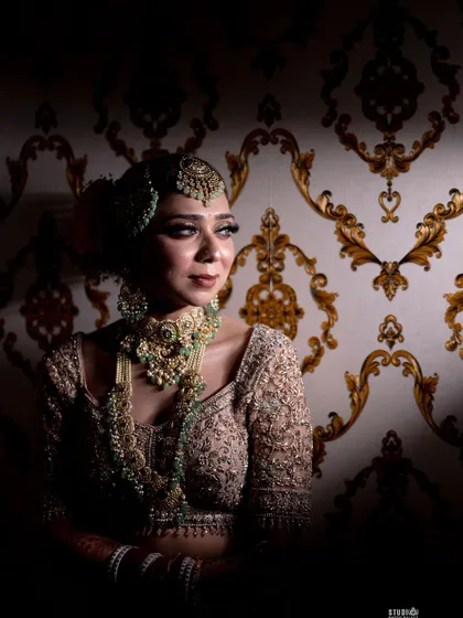 A moment of quiet elegance. The contrast between the dark background and the bride's illuminated face highlights the skillful makeup application and the richness of her traditional attire.