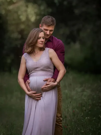 A duplicate of ID 60, this gentle and loving outdoor portrait shows a husband standing behind his wife, his arms wrapped around her as they both look down at her belly.