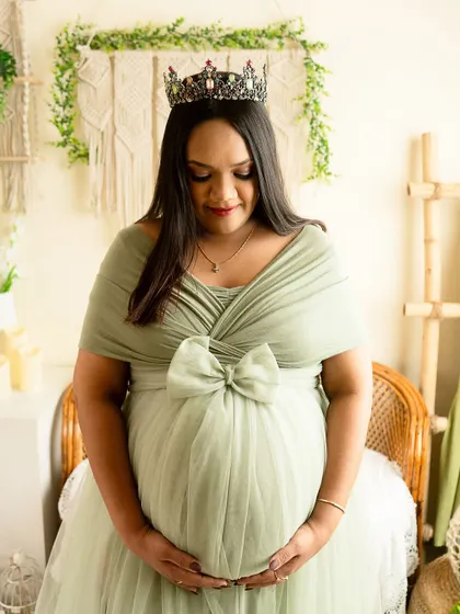 A close-up portrait in a soft, sage green gown. The crown and gentle downward gaze create a feeling of serene royalty.
