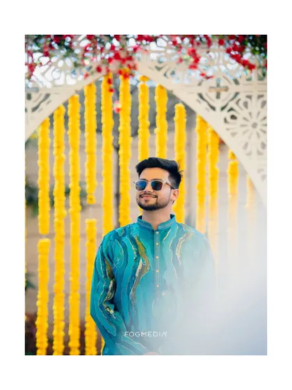 A stylish portrait of the groom against a backdrop of yellow marigolds, looking sharp for the Haldi.