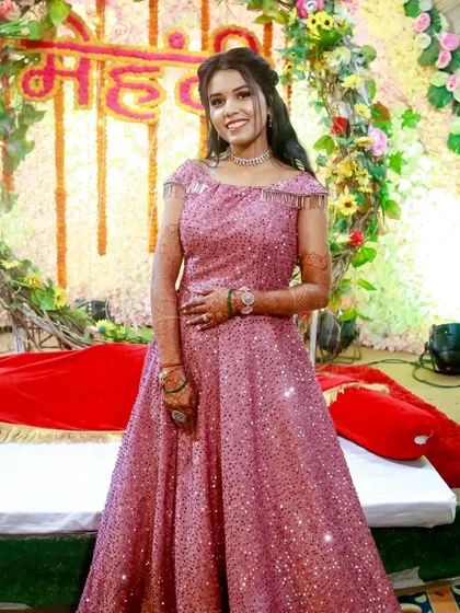 A happy client at her Mehendi ceremony in a sparkling pink gown. The off-shoulder design with fringe details is fun and festive.