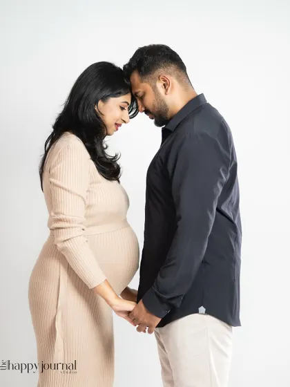 A quiet, intimate moment between a couple, their foreheads touching as they hold hands. This pose beautifully symbolizes their partnership and the new life they've created together.