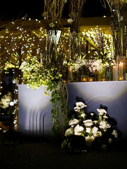 A corner decorated with lush greens, white flowers, and an abundance of fairy lights, adding to the magical, twilight-garden feel of the event.