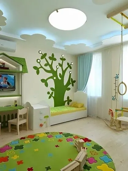 A nature-themed kids' room with a cloud-shaped false ceiling and a tree decal on the wall. The space also includes a small jungle gym, encouraging active play.