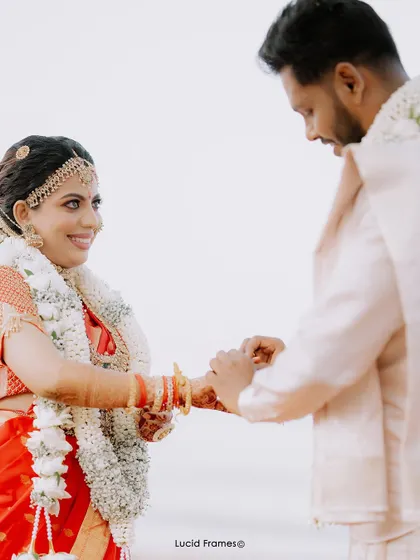 A moment of connection as the groom holds the bride's hand during their beachside ceremony.